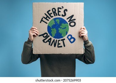 Unrecognizable man holding carton placard with Theres no planet B and hiding his face behind it in front of the camera. Concept of eco activism