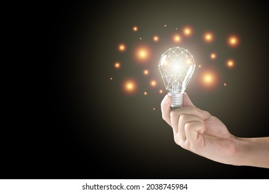 Unrecognizable Man Holding The Illuminated Vintage Tungsten Lightbulb On The Black Background With Copyspace. Creativity And Idea Concept. Lightbulb With Network Line.