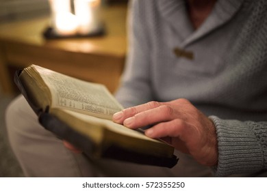 Unrecognizable Man At Home Reading Bible, Burning Candles Behind