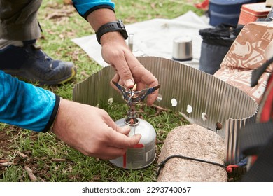 Unrecognizable man lighting a camp stove to cook at a campsite. Concepts: backpacking travel, camping lifestyle. - Powered by Shutterstock