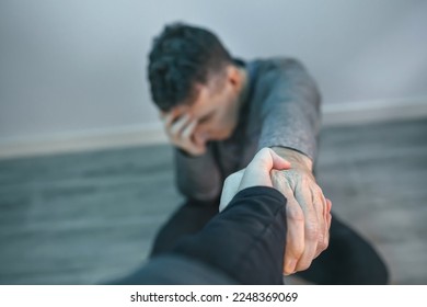 Unrecognizable man with problems receiving help from woman holding her hand. Helping hand concept