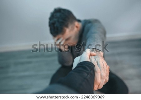 Unrecognizable man with problems receiving help from woman holding her hand. Helping hand concept