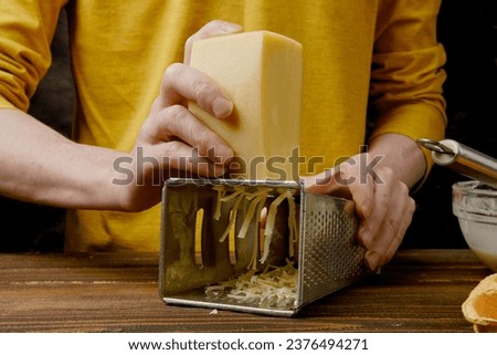 Unrecognizable man shredding cheese with metal grater