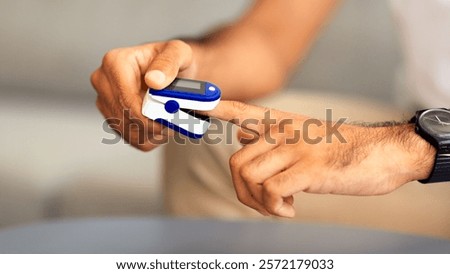 Unrecognizable man using modern pulse oximeter, closeup photo, copy space. Cropped of male patient putting clip-like small device for blood oxygen, saturation measuring and coronavirus