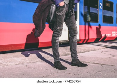 Unrecognizable man waiting for the train while standing on railroad station platform.