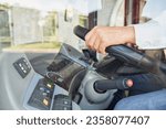 Unrecognizable man wearing shirt driving intercity bus at daytime. Crop view of male professional bus driver steering wheel at work. Concept of transportation, work place.