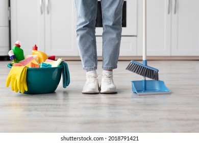 Unrecognizable man or woman in casual outfit cleaning apartment, standing by basket with cleaning supplies and holding mop, panorama. Female or male legs over home interior, house-keeping concept