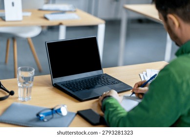 Unrecognizable Man Writing Notes While Using Laptop At Modern Office Desk, Productivity Concept