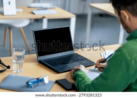 Unrecognizable Man Writing Notes While Using Laptop At Modern Office Desk, Productivity Concept