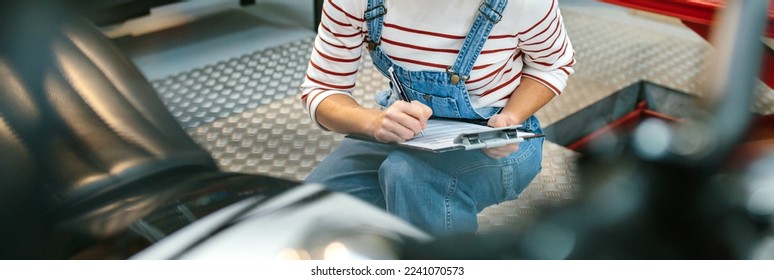 Unrecognizable mechanic woman with clipboard checking motorcycle and taking notes on factory - Powered by Shutterstock