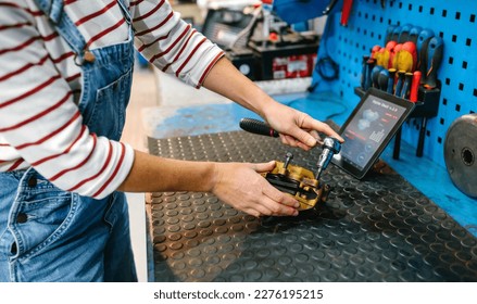 Unrecognizable mechanic woman repairing caliper brake system over garage workbench with diagnosis app in digital tablet on background - Powered by Shutterstock