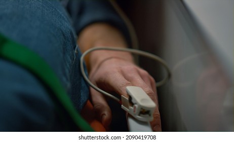 Unrecognizable Medical Worker Putting Pulse Oximeter On Patient Finger. Female Paramedic Checking Man Oxygen Blood Level. Closeup Male Victim In Oxygen Mask Lying On Stretchers In Emergency Car