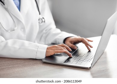 Unrecognizable Millennial Hindu Lady Therapist In White Coat Work At Workplace On Laptop In Clinic, Close Up. Modern Medicine And Online Visit To Doctor, Health Care, Video Chat And Advice To Patient