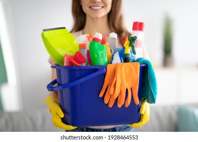 Unrecognizable millennial maid holding bucket with cleaning supplies indoors, closeup of hands. Cropped view of housewife with detergents, ready for house cleanup. Sanitary service concept