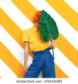 Unrecognizable Model holding palm leaf and wearing vintage look on trendy striped yellow background. Minimal fashion spring summer concept. Stylish colours combination.