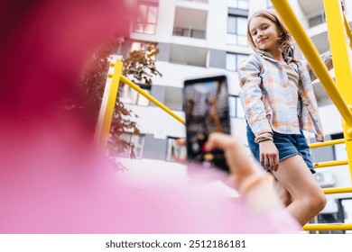 Unrecognizable mother shooting with smartphone preteen daughter l sitting on monkey bars at playground outdoor. Kid, adventure and fun on jungle gym playground, balance or energy for physical growth. - Powered by Shutterstock