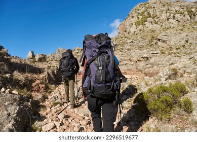 Unrecognizable mountaineers hiking up a trail amidst a rocky mountain landscape in Los Gigantes, Cordoba, Argentina, an ideal tourist destination for trekking and climbing. - Shutterstock ID 2296519677