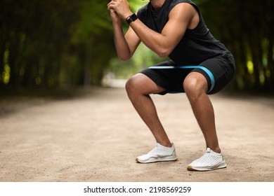 Unrecognizable Muscular Black Man Exercising In Public Park, Using Elastic Fitness Band, Enjoying Outdoor Workout, Panorama With Copy Space, Cropped. Sports Lifestyle And Millennials