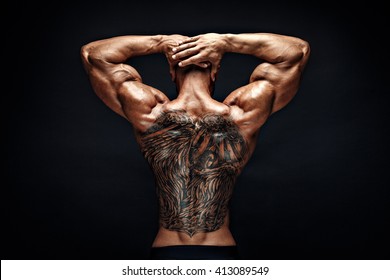 Unrecognizable muscular man with tattoo on back against of black background.Isolated.