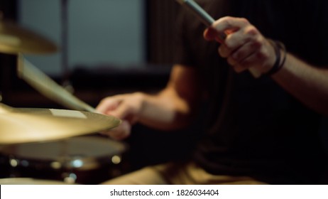 Unrecognizable musician hands hitting drum plates in recording studio. Close up of drummer hands performing solo with drumsticks. Attractive artist playing on drum kit indoor.