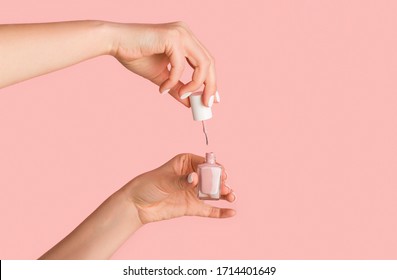 Unrecognizable Nail Tech Opening Bottle Of Polish On Pink Background, Close Up. Empty Space