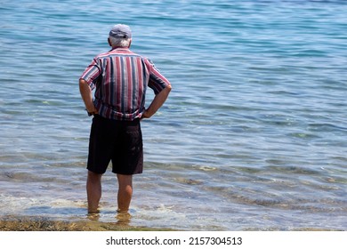 Unrecognizable Old Man Standing On The Beach And Looking At The Sea. Sunny Summer Day
