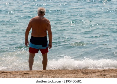 Unrecognizable Old Man Standing On The Beach And Looking At The Sea. Sunny Summer Day