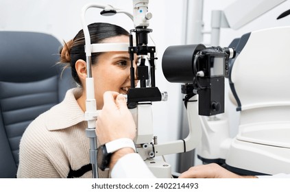 An unrecognizable ophthalmologist uses a slit lamp with a camera to examine a woman's eye. Biomicroscope.Eye health concept. Observation of the surface of the anterior pole of the eyeball - Powered by Shutterstock