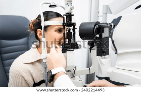 An unrecognizable ophthalmologist uses a slit lamp with a camera to examine a woman's eye. Biomicroscope.Eye health concept. Observation of the surface of the anterior pole of the eyeball