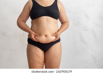 Unrecognizable Overweight Obese Woman In Black Bikini Touching And Squeezing Big Dangling Tummy. Hand Self Massage To Friable Cellulite Skin. Food Addiction, Obsession, Overeating Problem. Health Care