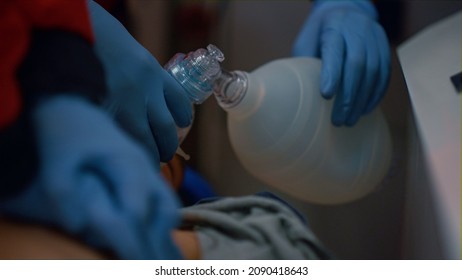 Unrecognizable Paramedics Hands Providing Cardiac Massage On Chest Of Patient. Medical Workers Using Respiratory Mask For Ventilation Man Lungs With Coronavirus Pneumonia. Ambulance Doctors Doing CPR