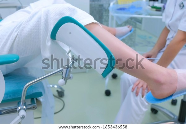 Unrecognizable patient woman in\
gynecological chair in clinic, side view. Modern interior in\
medical office. Doctor gynecologist preparing to inspection.\
Examination and consultation of\
gynecologist.