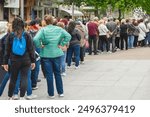 Unrecognizable people standing in queue outdoors, municipal or other public event