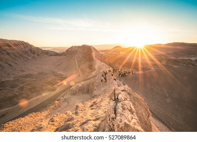 Unrecognizable people tourists watching sunset on rock formation mountain at " Valle De La Luna " in world famous Atacama desert in Chile - Adventure hiking trip to south latin america nature wonder