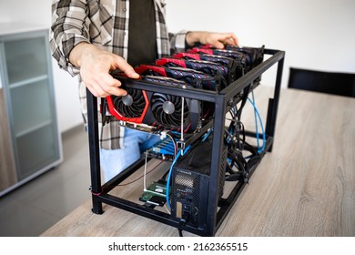 Unrecognizable person or an expert building new mining rig for bitcoin cryptocurrency. Blockchain technology and graphic cards in row.