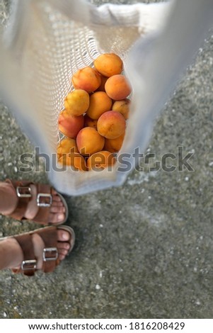 Unrecognizable person holding a bag of apricots. Top view, selective focus.