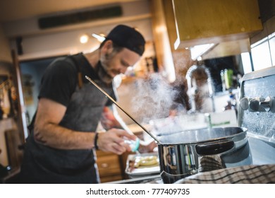 Unrecognizable Person Parboiling And Salting Pretzel In Pot With Boiling Water Before Cooking.