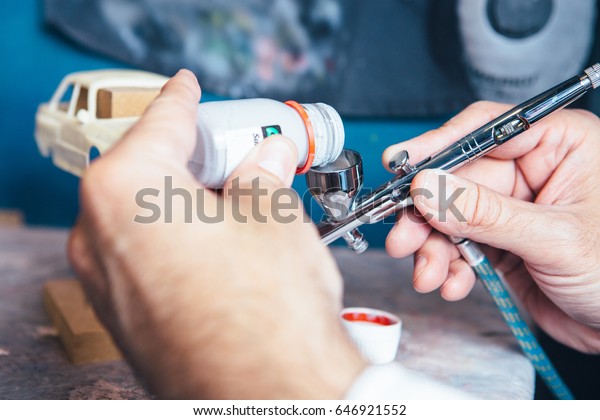 Unrecognizable person pouring paint to airbrush\
for slot car\
painting.
