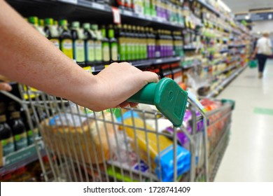Unrecognizable person pushing a shopping trolley full of groceries in a supermarket keeping social distancing. COVID -19 (Coronavirus) restrictions concept.