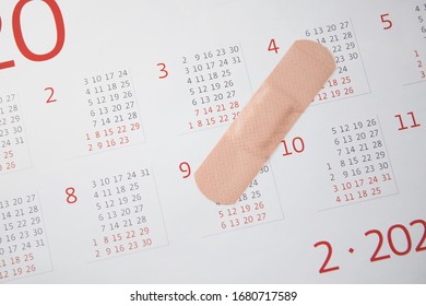 Unrecognizable person sticking a medical patch on the surface of calendar for 2020. Concept of the raging coronavirus pandemic in 2020