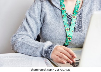 Unrecognizable Person Studies Or Works At Home With A Notebook Using A Sunflower Lanyard, Symbol Of People With Invisible Or Hidden Disabilities.