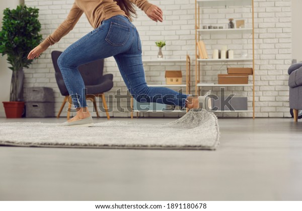Unrecognizable person trips over rug at home.\
Clumsy faceless woman in uncomfortable shoes stumbles on rug in\
living-room and falls down on floor. Concept of getting injured in\
domestic\
accidents