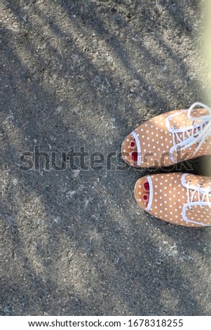 Unrecognizable person wearing quirky polka dot sandals. Top view. 