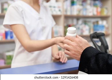 Unrecognizable pharmacist and customer in drugstore. Hand of man taking medicament, client buying in pharmacy. Chemist giving white pill bottle for health care, from disease. - Shutterstock ID 1291426408
