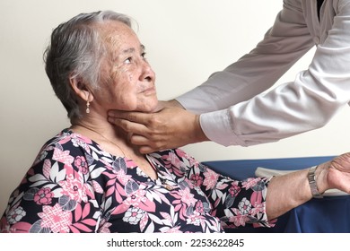 unrecognizable physician palpating carotid pulse of elderly woman