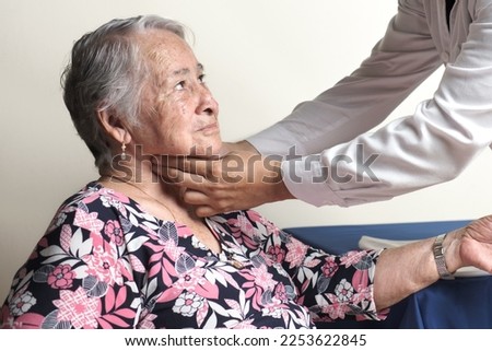 unrecognizable physician palpating carotid pulse of elderly woman