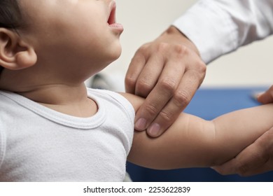 unrecognizable physician's hands palpating humeral brachial pulse in infant patient