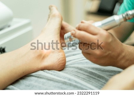 An unrecognizable podiatrist performs laser therapy on an athlete's foot. Laser therapy treatment, laser in podiatry. Foot care in medical centers.