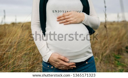 Foto Bild Schwanger mit Partner, der sich umarmt und den nackten Bauch hält.