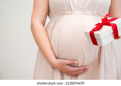 unrecognizable pregnant woman holding gift with red ribbon.Mother's day,valentine's,baby shower concept